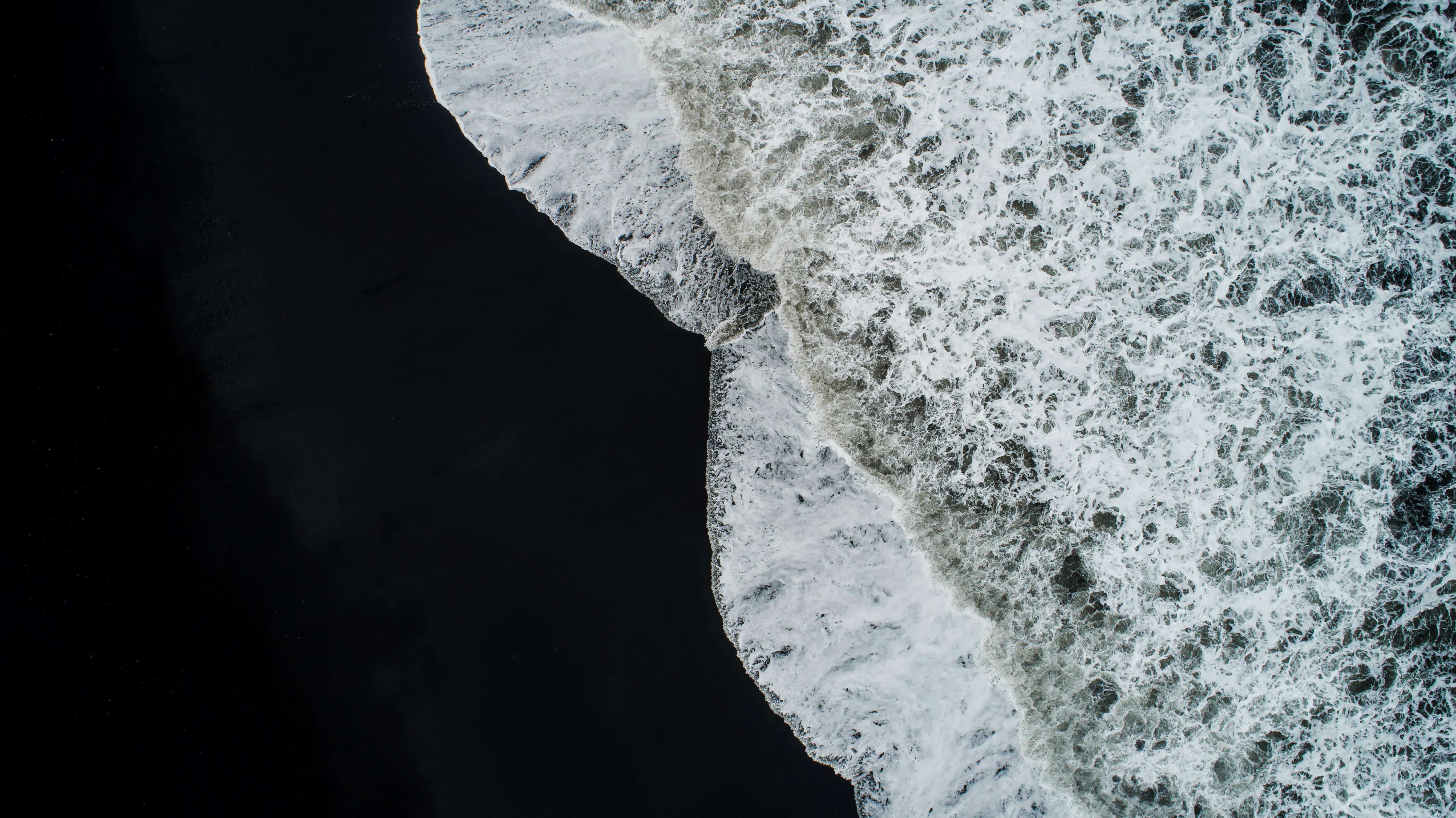 En sort strand med hvide bølger, der slår
